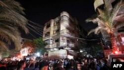 Warga Palestina berkumpul di depan sebuah gedung saat petugas pemadam kebakaran berupaya memadamkan api yang berkobar di salah satu apartemen di kamp pengungsi Jabaliya di jalur Gaza utara, 17 November 2022.(MAHMUD HAMS/AFP)