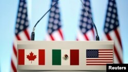 FILE - The flags of Canada, Mexico and the U.S. are seen on a lectern before a joint news conference on the closing of the seventh round of NAFTA talks in Mexico City, Mexico, March 5, 2018. 