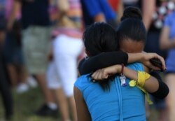 FILE - People grieve during a vigil for victims behind the theater where a gunman opened fire on moviegoers in Aurora, Colorado, July 20, 2012.