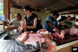 Priscila Deus De Olivera, second from left, prepares pirarucu pieces to cook, at San Raimundo settlement in Carauari, Brazil, Sept. 5, 2022.