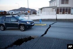 A car drives toward a fissure in a road in the town of Grindavik, Iceland, Nov. 13, 2023 following seismic activity.