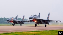 FILE - In this undated photo released by China's Xinhua News Agency, two Chinese SU-30 fighter jets take off from an unspecified location to fly a patrol over the South China Sea.