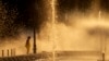 A municipal worker cools off next to a city fountain in Bucharest, Romania, July 11, 2024, as temperatures exceeded 39 degrees Celsius.