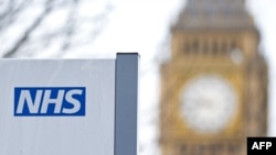 FILE - An National Health Service sign is seen with the Big Ben clock face and the Elizabeth Tower in the background, in London, Britain, Jan. 13, 2017.