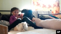 Ailyn Arriola, from the state of Michoacan, looks at her cellphone inside a room assigned for single mothers and their children in a shelter for migrants Dec. 21, 2022, in Tijuana, Mexico. 
