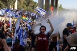 Israeli security forces use a water cannon to disperse demonstrators blocking the entrance of the Knesset, Israel's parliament, in Jerusalem, July 24, 2023.