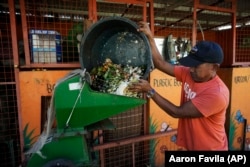 A worker pours garbage on a machine at a recycling facility in Malabon, Philippines on Monday Feb. 13, 2023. (AP Photo/Aaron Favila)