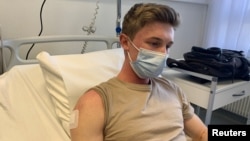 FILE - Volunteer Julien Oppliger rests after receiving a new generation COVID-19 vaccine administered via an arm patch during a Phase I clinical study, led by Unisante at the University Hospital (CHUV) in Lausanne, Switzerland, Jan. 19, 2022. (REUTERS/Cecile Mantovani)