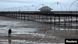 ፋይል፡ አንድ ሰው በብሪታንያ ሳውዝፖርት ፒየር ፊት ለፊት ባለው የባህር ዳርቻ ላይ በብረት መመርመርያ የተቀበረ ነገር ሲፈልግ ያሳያል፣ የካቲት 12 ቀን 2016 ዓ.ም.