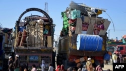 Pengungsi Afghanistan duduk di samping barang-barang mereka di pusat pendaftaran setibanya mereka dari Pakistan, dekat perbatasan Afghanistan-Pakistan di distrik Spin Boldak di provinsi Kandahar, 20 November 2023. (Sanaullah SEIAM/AFP)