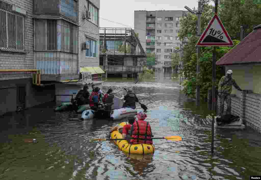 Local residents sail on boats at a flooded street during an evacuation from a flooded area after the Nova Kakhovka dam breached, in Kherson, Ukraine, June 8, 2023.