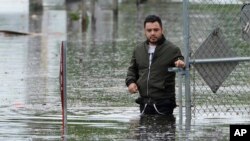 Francisco Lopez stands near the flooded parking lot of his apartment building, June 13, 2024, in Hallandale, Fla. 