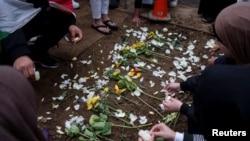 FILE - Mourners place flowers at the grave of Wadea Al-Fayoume, 6, at Parkholm Cemetery in LaGrange, Illinois, Oct. 16, 2023.