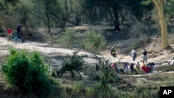 FILE — Zimbabweans wait to cross into South Africa on the dry bed of the Limpopo river, east of the border town of Musina, South Africa, June 30, 2020.