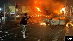 Flames rise from a car and a bus, set alight at the junction of Bachelors Walk and the O'Connell Bridge, in Dublin, Nov. 23, 2023, as people took to the streets in protest following stabbings earlier in the day.