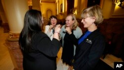 From left, state Sens. Julie Gonzales and Sonya Jaquez Lewis and Reps. Meg Froelich and Karen McCormick bump fists after Colorado's governor signed three bills enshrining protections for abortion and gender-affirming care, April 14, 2023, in Denver.
