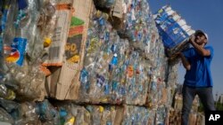 FILE - Worker carries compressed plastic bottles from the Nile to build Plastic Pyramid, in Cairo, Egypt, Sept. 15, 2022, to raise awareness on plastic pollution in the Nile.