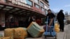 FILE - Men move bags of goods for export in front of a trading center that houses shops and offices with Russian goods and services, in Beijing, April 1, 2022.