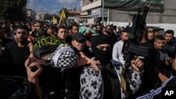 Mourners carry the bodies of three Palestinians draped in the Hamas and Islamic Jihad militant group flags during their funeral in the Jenin refugee camp, West Bank, Nov. 17, 2023.