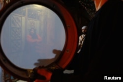 Seorang perempuan Palestina menonton penampilan kelompok Mesaharati, saat mereka membangunkan umat Islam untuk makan sahur pada bulan suci Ramadan, di Khan Younis, selatan Jalur Gaza 25 Maret 2023. (REUTERS/Ibraheem Abu Mustafa)