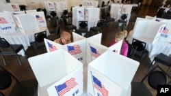 Para pemilih mengisi surat suara mereka untuk pemilihan pendahuluan Michigan di Grosse Pointe Farms, Michigan, Selasa, 27 Februari 2024. (AP/Paul Sancya)