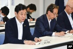 Japan's Industry Minister Yasutoshi Nishimura, left, meets with fisheries officials, not in photo, in Iwaki, Fukushima prefecture, northern Japan, Saturday, June 10, 2023. (Kyodo News via AP)