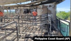 In this handout photo provided by the Philippine Coast Guard (PCG), PCG members check the remains of the MV Lady Mary Joy that caught fire in Basilan, southern Philippines early Thursday, March 30, 2023. (Philippine Coast Guard via AP)