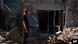 Dmytro Ihnatenko, owner of the destroyed Ria Pizza, stands beside a wide hole left from an Iskander missile that hit his business in June, in Kramatorsk, Ukraine, Sept. 13, 2023. 