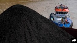 FILE - A tug boat pushes a barge carrying coal on Mahakam river in Samarinda, East Kalimantan, Indonesia, Dec. 19, 2022.