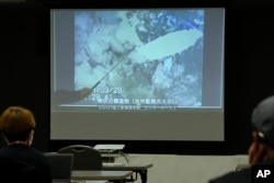 A spokesperson of the Tokyo Electric Power Company Holdings (TEPCO) shows photos captured by a robotic probe inside one of the three melted reactors at the tsunami-wrecked Fukushima nuclear power plant, Tuesday, April 4, 2023. (AP Photo/Shuji Kajiyama)