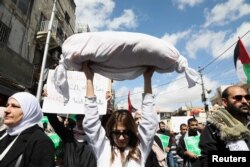 FILE - A demonstrator holds rolled up white cloth during a protest in support of Palestinians in Gaza, amid the ongoing conflict between Israel and Palestinian Islamist group Hamas, in Amman, Jordan, March 15, 2024.