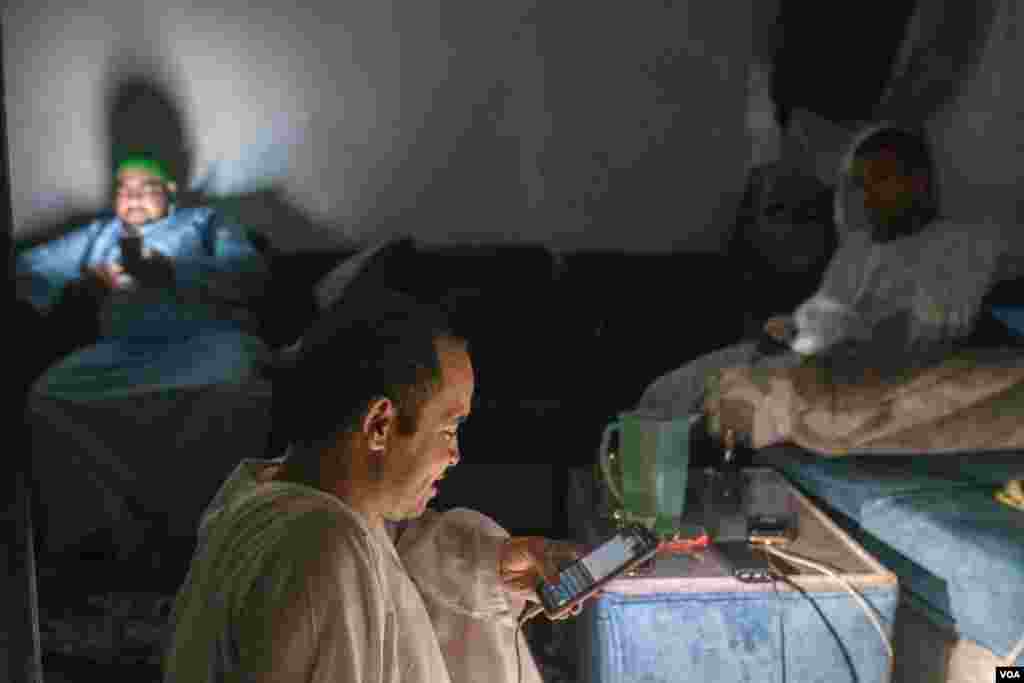 This family gets by with a phone light during the regular power outages that the Egyptian government blames on soaring electric power consumption driven by the latest heat waves. (Hamada Elrasam/VOA) 