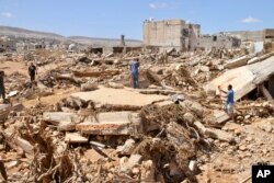 Warga mencari korban selamat di Derna, Libya, Rabu, 13 September 2023. Tim pencari mencari jenazah di Derna, tempat runtuhnya dua bendungan yang memicu banjir bandang besar yang menewaskan ribuan orang. (Foto: AP/Yousef Murad)