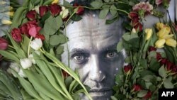 Bunga-bunga di sekitar potret pemimpin oposisi Rusia yang sudah meninggal, Alexey Navalny, di sebuah tugu sementara di depan bekas konsulat Rusia di Frankfurt am Main, Jerman, pada 19 Februari 2024. (Foto: AFP)