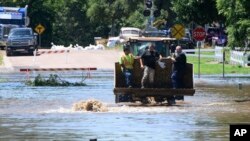 A person holds a dog while being evacuated in the bucket of a front end loader in Hawarden, Iowa, June 22, 2024, in the wake of flooding from the Big Sioux River.