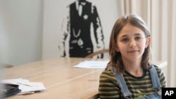 Ola Kozak, 11, sits at the table where she used to do her homework at her home in Warsaw, Poland, April 5, 2024. Ola is happy Poland's government has limited the amount of homework teachers can impose on students in lower grades.
