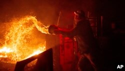 Francis Lopez se bori protiv plamena bacajući vodu iz kofe, tokom požara Hajlend fajer, na svom imanju u Aguandžu, Kalifornija, 30. oktobar 2023.