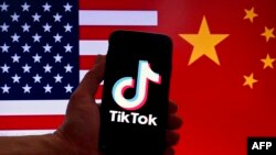 FILE - In this photo illustration the social media application logo for TikTok is displayed on the screen of an iPhone in front of a US and Chinese flag background in Washington, DC, on March 16, 2023. 