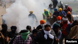 Farmers, who are marching towards New Delhi to press for better crop prices, run for cover amidst tear gas fired by police to disperse them at Shambhu barrier, a border crossing between Punjab and Haryana states, India, Feb. 21, 2024.