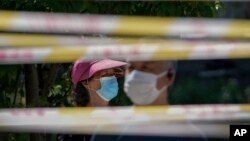 FILE - Residents line up behind tape barricades for COVID testing, May 15, 2022, in Beijing. Chinese officials say they have not detected any unusual new diseases in the country, the World Health Organization said Nov. 23, 2023.