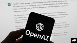 The OpenAI logo is seen on a mobile phone in front of a computer screen which displays output from ChatGPT, March 21, 2023, in Boston.(AP Photo/Michael Dwyer, File)