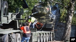 FILE - Workers remove a Soviet T-34 tank installed as a monument in Narva, Estonia, Aug. 16, 2022. Russia's invasion of Ukraine has led to a renewed push to topple the last remaining monuments to the Soviet army that remained in Europe. 