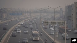 Pengendara sepeda motor berkendara dengan mengenakan masker polusi di tengah kabut asap di New Delhi, India, Selasa, 7 November 2023. (Foto: AP)