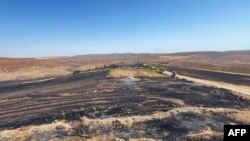 This handout photograph taken and released June 21, 2024, by Turkish news agency DHA shows a burnt field after a wildfire swept through two areas between the districts of Diyarbakir and Mardin in southeastern Turkey. 
