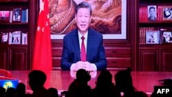 Para pengunjung restoran sedang menyantap makan malam sementara televisi menyiarkan pidato Tahun Baru oleh Presiden China Xi Jinping di Beijing, China, Minggu, 31 Desember 2023. (Foto: Pedro Pardo/AFP)