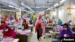 FILE - Women work in a garment factory, as factories reopened after the government has eased the restrictions amid concerns over the COVID-19 outbreak in Dhaka, Bangladesh, May 3, 2020. 