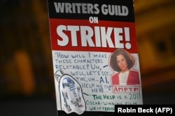 Selembar poster mogok kerja tampak di kerumunan demo para penulis naskah Hollywood di luar Universal Studios, Hollywood, di Los Angeles, California, Jumat, 30 Juni 2023. (Foto: Robyn Beck/AFP)