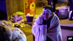 An ethnic Armenian woman from Nagorno-Karabakh warms herself near a tent camp after arriving in Armenia's Goris in Syunik region, Armenia, Sept. 29, 2023. 
