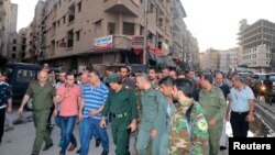 People and internal security members inspect the site of a bomb blast, outside the Sayeda Zeinab shrine city, south of the Syrian capital Damascus, Syria, July 27, 2023. (SANA/Handout via Reuters)