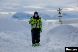 Plumber and Kings Bay AS watchman Jakob Weiset, 31, uses his radio in front of a polar bear warning sign marking the settlement's safe area in Ny-Aalesund, Svalbard, April 11 2023.